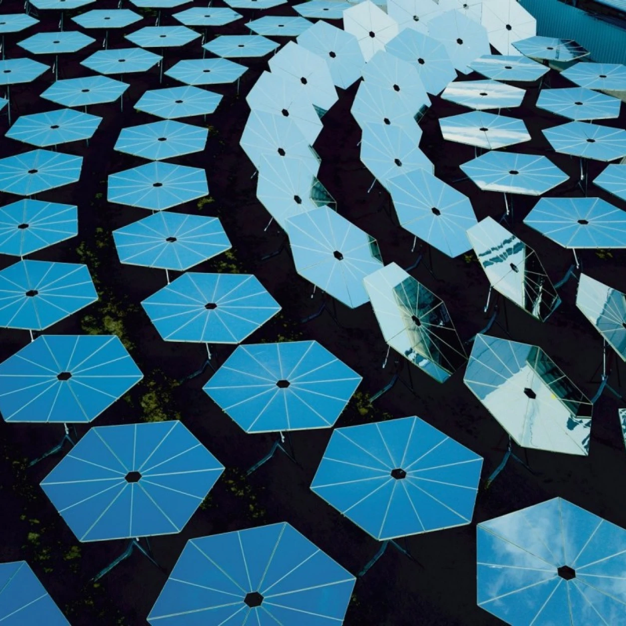 Aerial view of multiple blue solar panels arranged in a geometric patern, Synhelion facility
