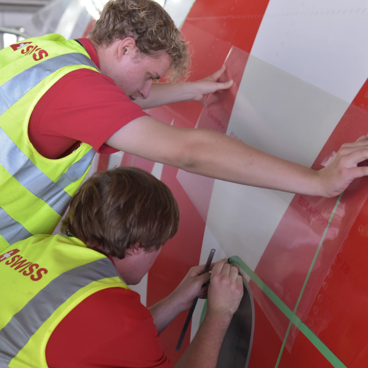 Tow young workers working on a plane applying AEROShark technology foil on aircarft